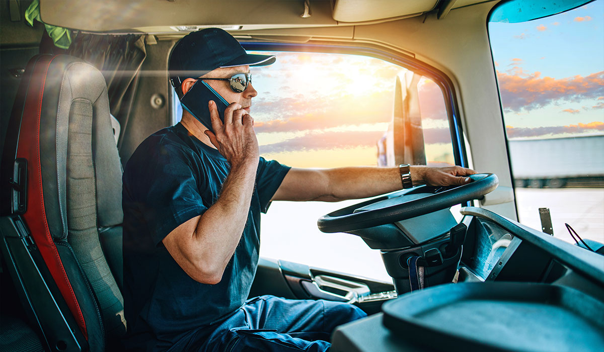 Man talking on his phone while sitting behind the wheel of a semi truck