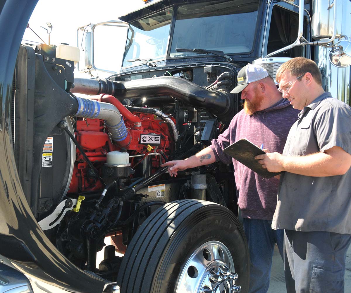 Mechanic with a clipboard inspecting a semi truck