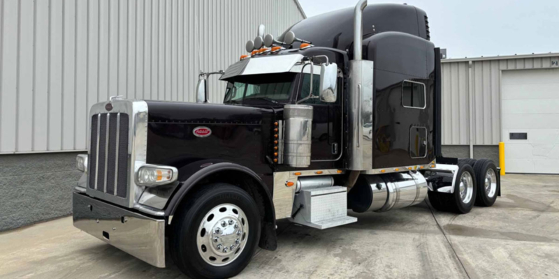 A black peterbilt 379 semi truck parked in front of a building