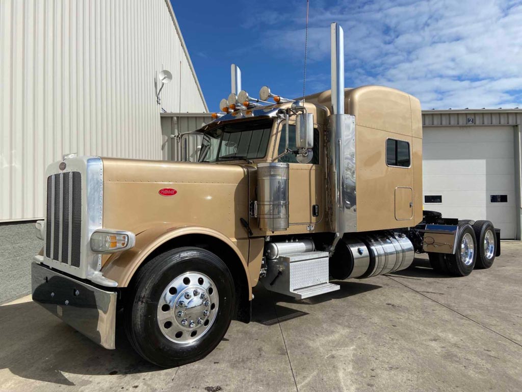 A tan peterbilt 389 semi truck parked in front of a building