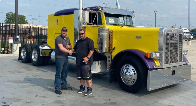 Happy salesperson posing with buyer in front of a Peterbilt semi truck