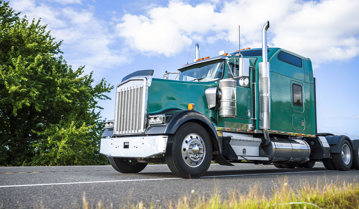 Green semi truck driving down the road