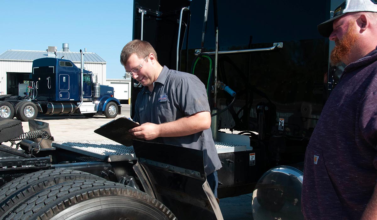 Employee inspecting a semi truck with a clipboard