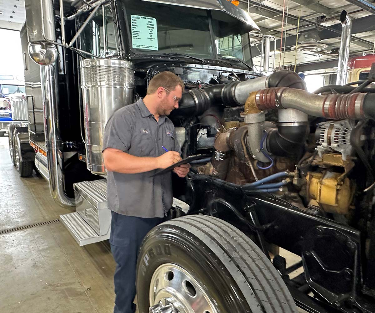 Mechanic with a clipboard inspecting a semi truck