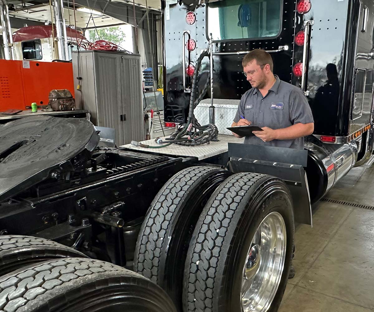 Mechanic with a clipboard inspecting a semi truck